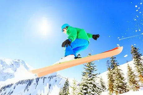 Snowboarder mid-air performing a jump on a bright sunny day.