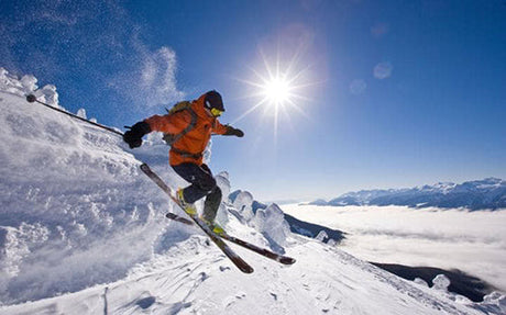 Skier in mid-action on a snowy slope with bright sunlight overhead.