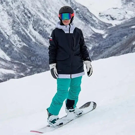 Snowboarder in black jacket and teal pants showcasing stylish women jackets on snow.