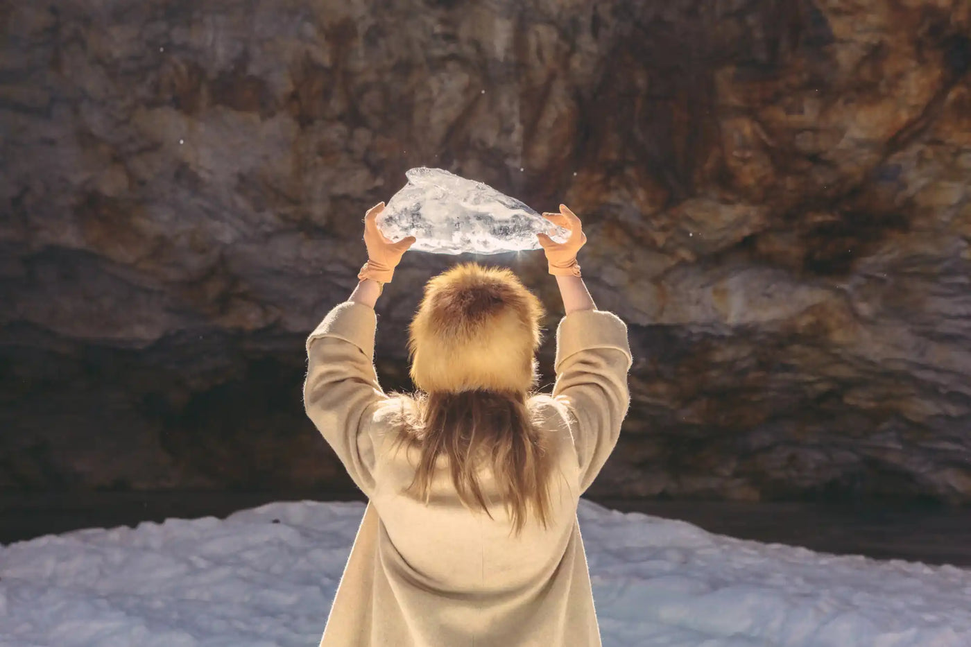 Person holding a chunk of ice or snow above their head.