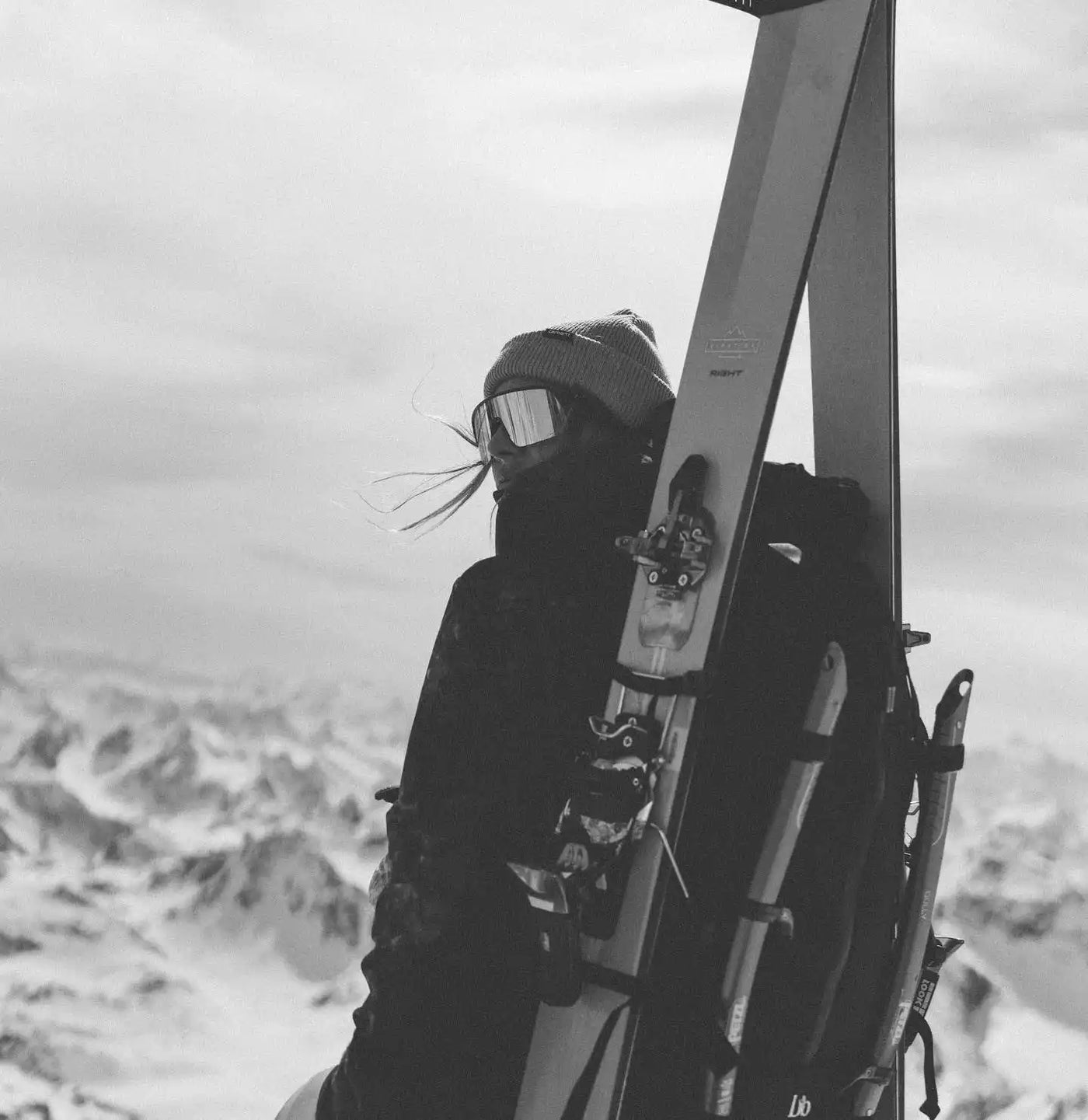 Skier in dark clothing carrying skis on a snowy mountain peak.